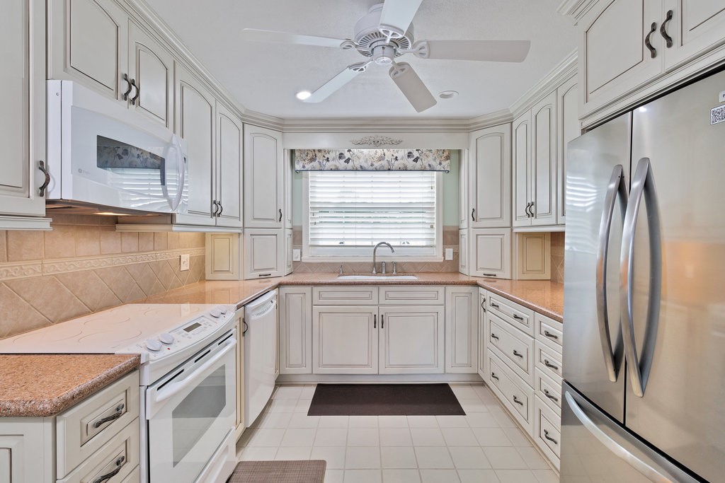 U-shaped kitchen featuring white cabinetry, light-toned countertops, and a tiled backsplash
