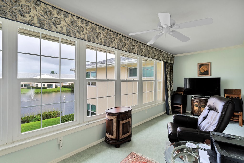 Spacious interior room featuring a wall of multiple pane windows, a ceiling fan, and light green wall paint