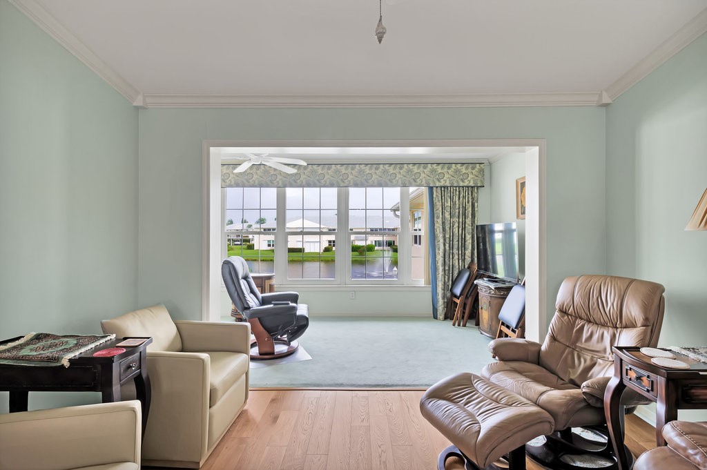 Sunken living area with a large picture window, crown molding, and wood-finish flooring