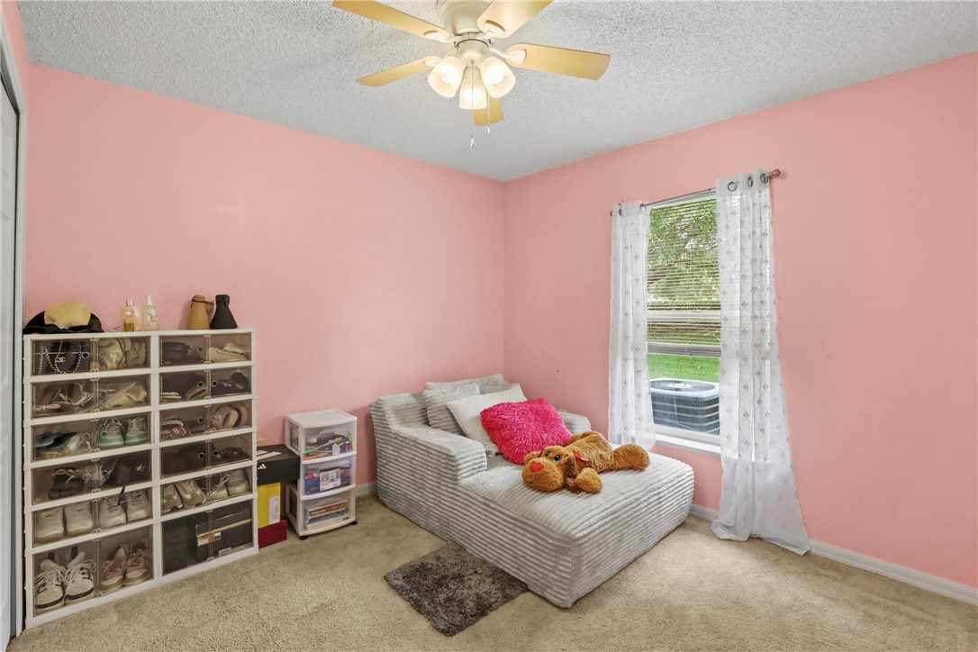 Carpeted room featuring a single window with white trim, a textured popcorn ceiling, and a ceiling fan with light fixture