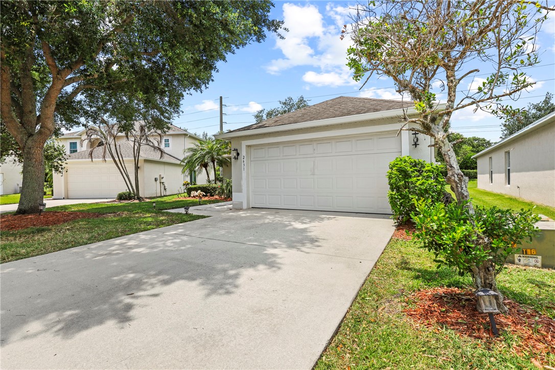 Front exterior featuring a two-car garage, concrete driveway, and mature landscaping