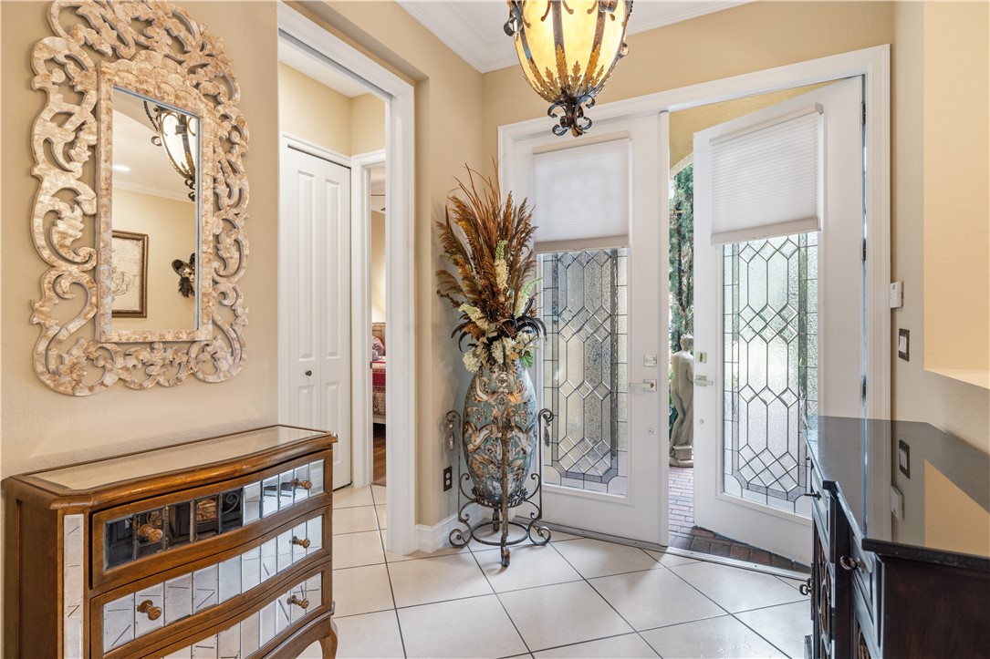 Entryway featuring a decorative chandelier, dual glass-paneled entry doors with geometric details, and light-toned tile flooring