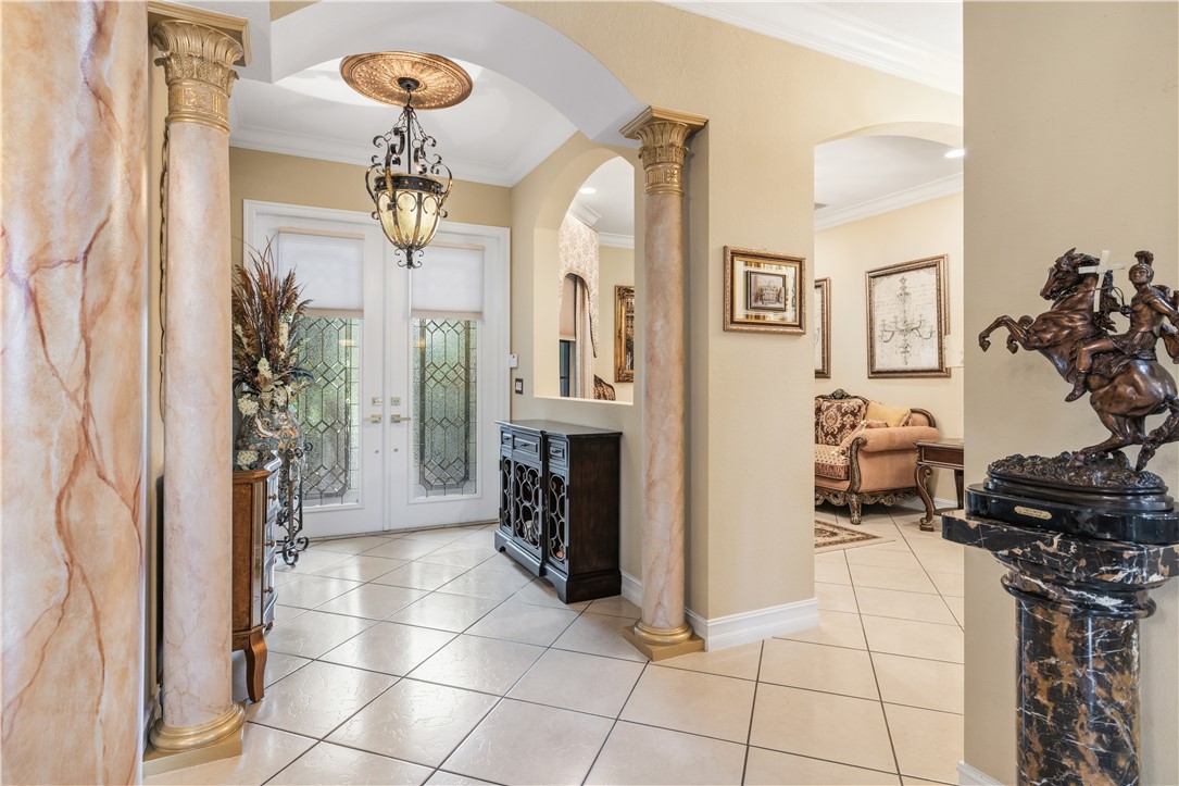Grand entryway featuring double doors with decorative glass panels, a detailed overhead light fixture, and tile flooring
