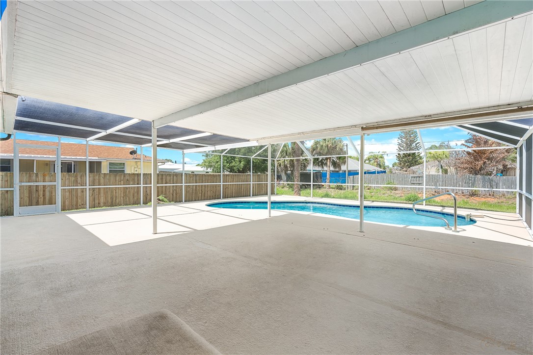 Screened outdoor living area with a built-in swimming pool and expansive concrete patio