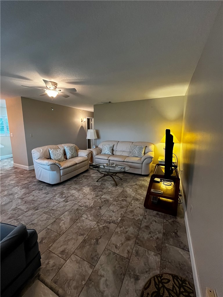 Expansive living area featuring large format tile flooring, a ceiling fan with integrated lighting, and neutral wall tones