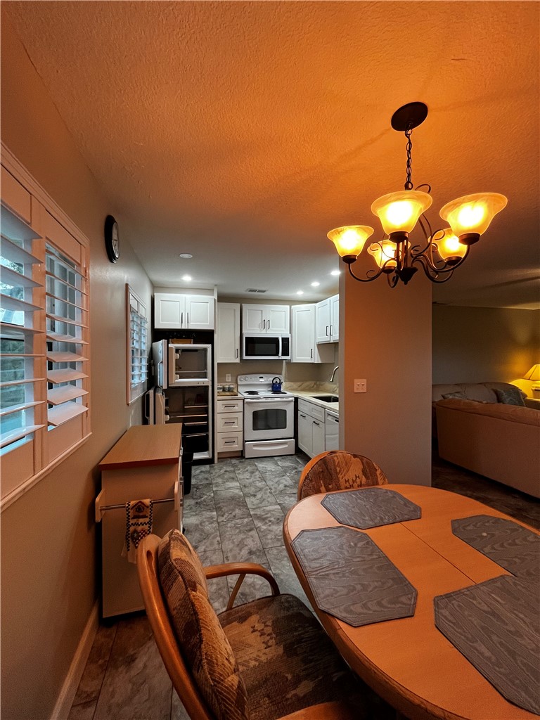 Kitchen and dining area featuring white cabinetry, a white electric range, a microwave, and a stainless steel refrigerator