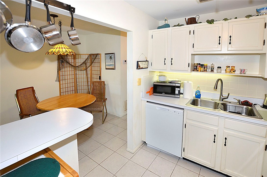 Kitchen featuring white cabinetry, white countertops, a stainless steel double basin sink, and a white dishwasher