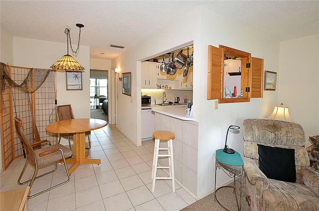 Kitchen with white cabinetry, a built-in pot rack, and a pass-through window with wooden shutters