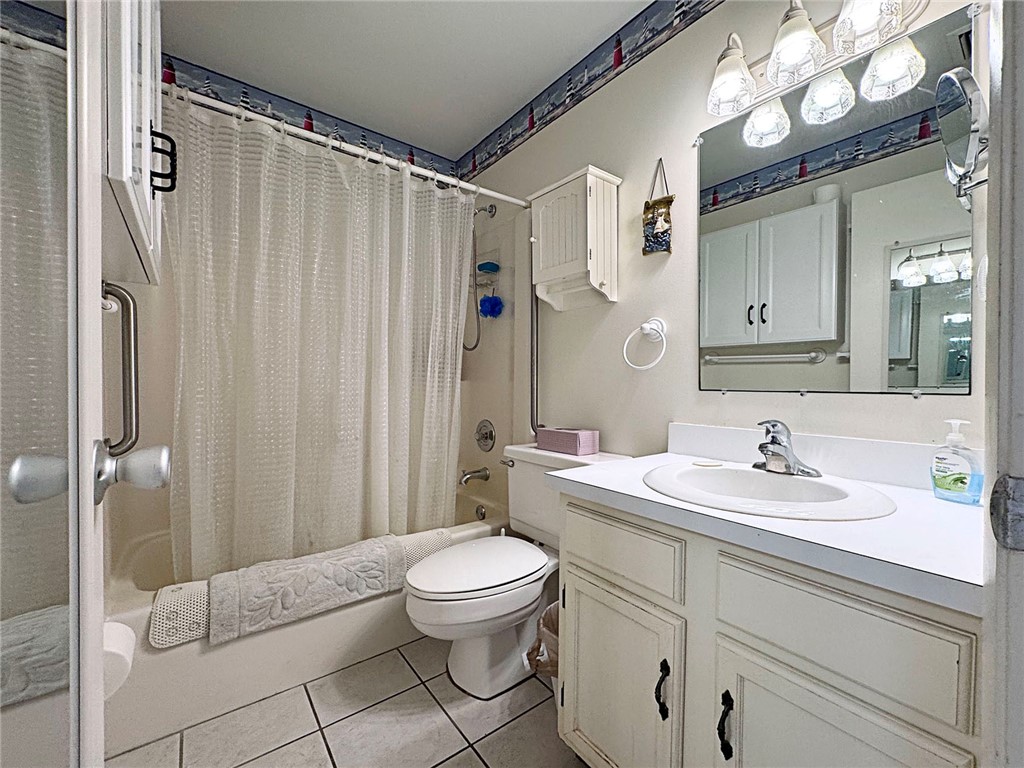 Bathroom featuring a vanity with a white countertop and integrated sink, a large wall mirror, and a white cabinet with dark hardware