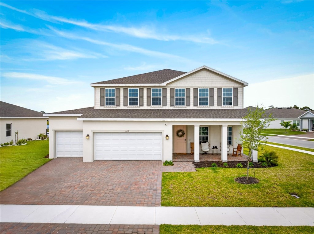 Two-story residence featuring a covered front porch, a three-car garage, and a paver driveway