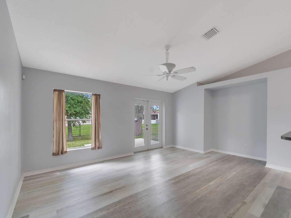 Spacious room featuring light gray walls, wood-finish flooring, and a white ceiling fan