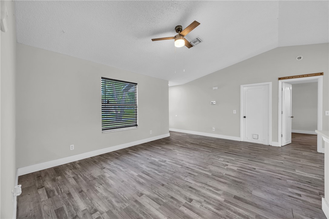 Open concept living area featuring wood-finish flooring, a vaulted ceiling, and a modern ceiling fan with light fixture