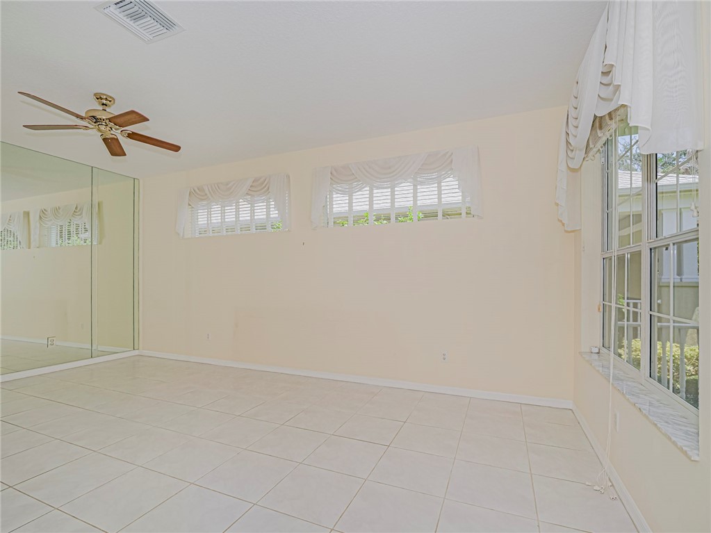Smooth tile flooring, full-height mirrored wall, single-pane windows, and a ceiling fan