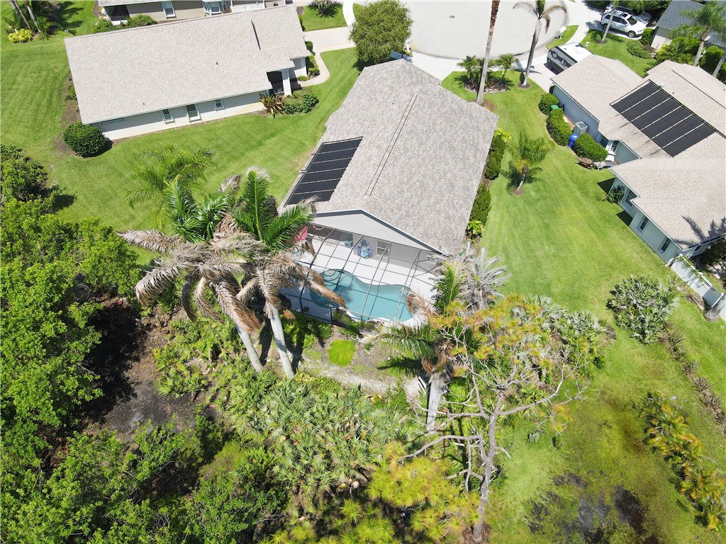 Aerial perspective featuring a single-story residence with a screened-in swimming pool