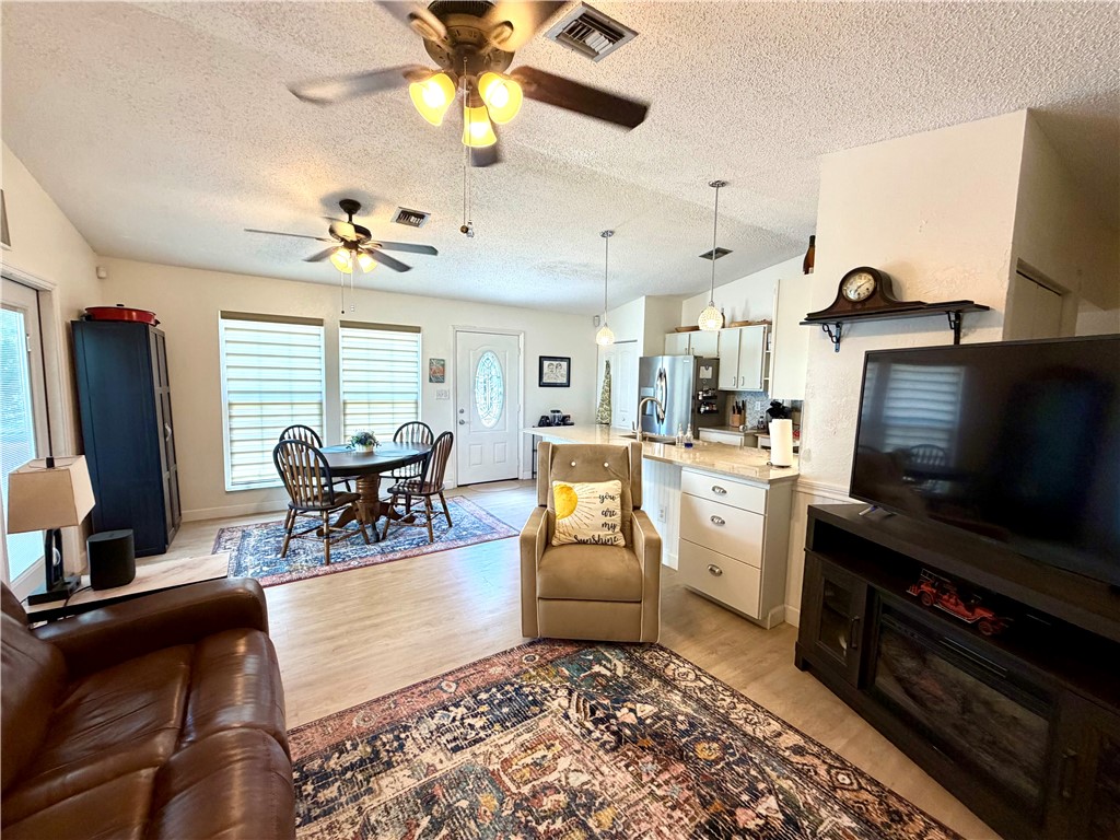 The interior features light-colored flooring, windows with horizontal blinds, and ceiling fans