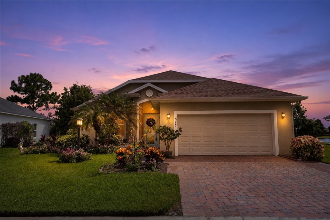Stucco exterior residence featuring a brick paver driveway