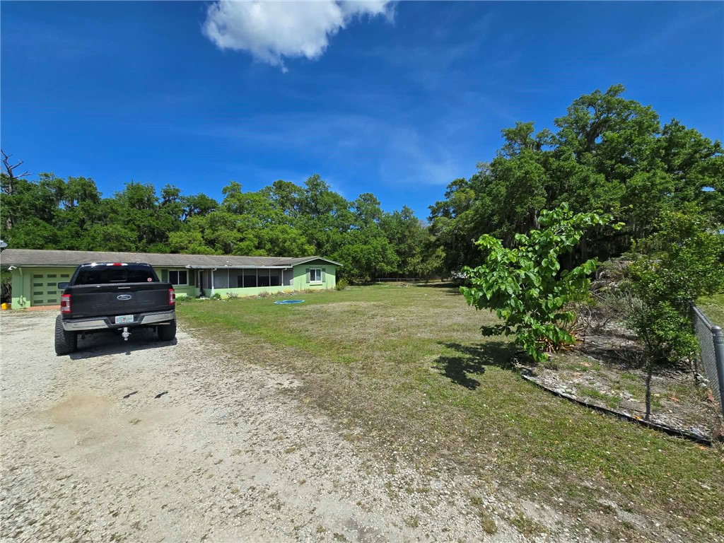 View of green lawn with driveway and a garage