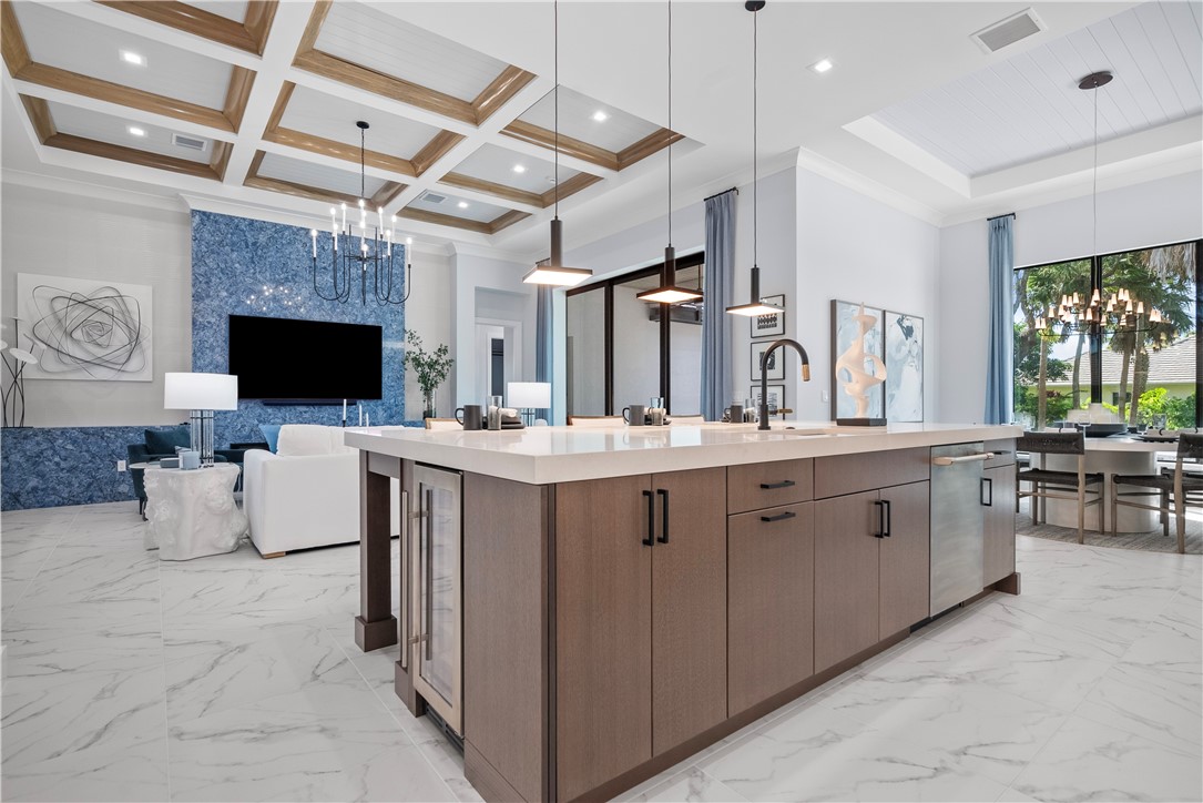 Kitchen with suspended lighting, open floor plan, light marble finish flooring, a large island, and crown molding