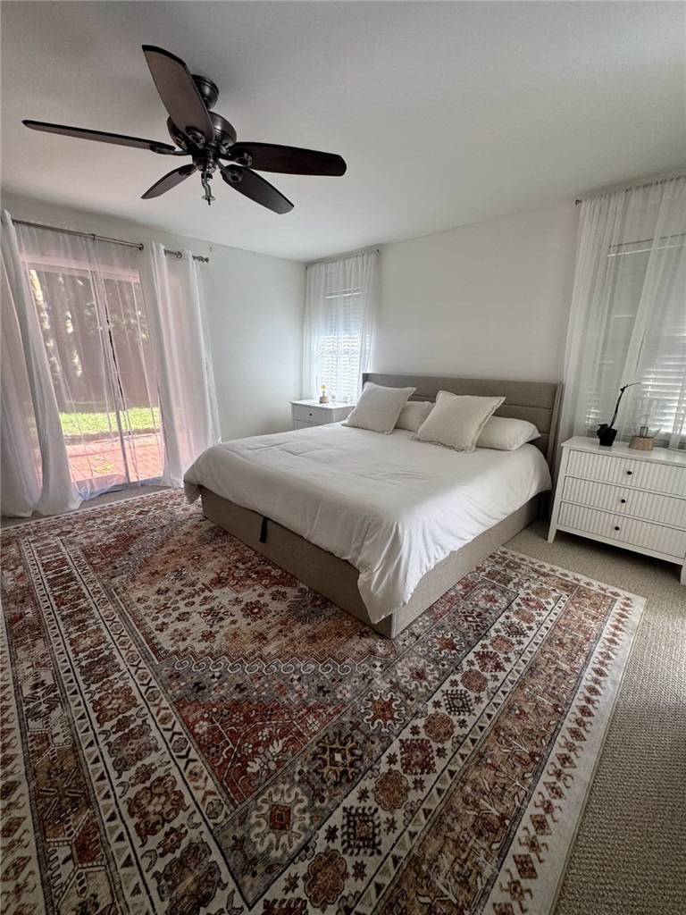 Carpeted bedroom with access to exterior and a ceiling fan