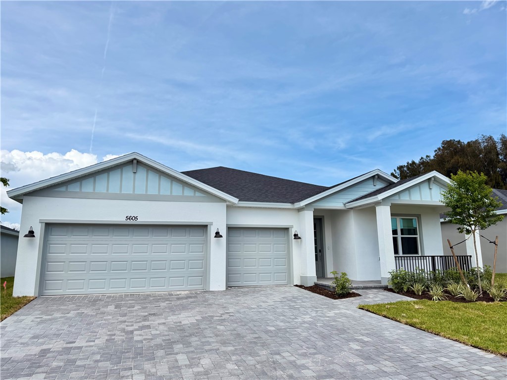 Ranch-style house with board and batten siding, decorative driveway, an attached garage, and stucco siding