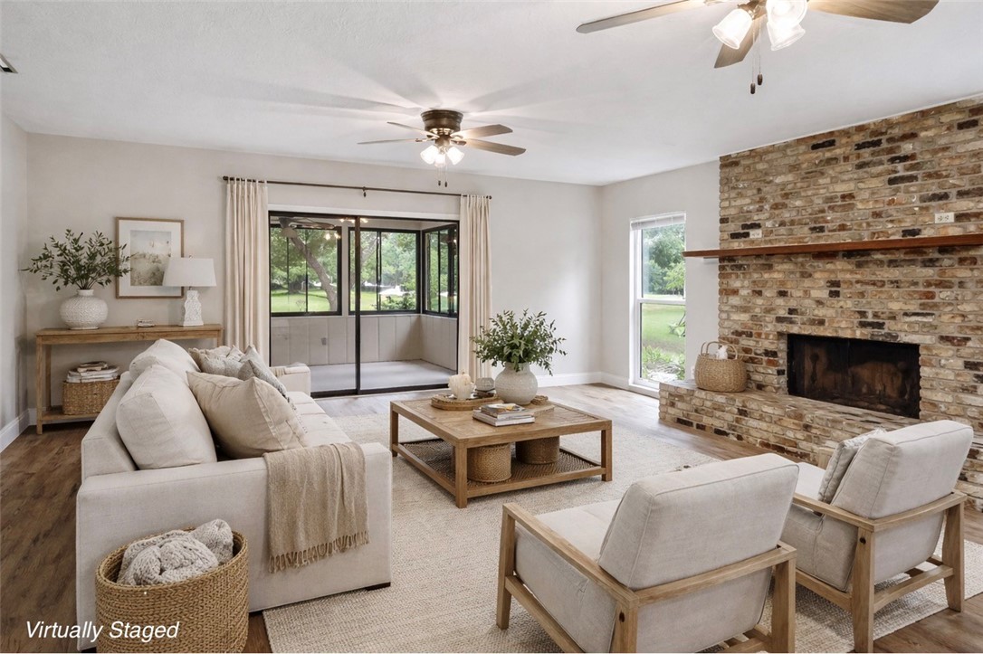 Living room with a ceiling fan, wood finished floors, and a fireplace