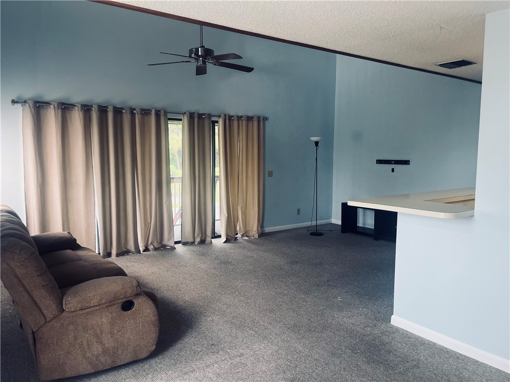 Vaulted ceiling with an integrated ceiling fan, light blue painted walls, and carpet flooring