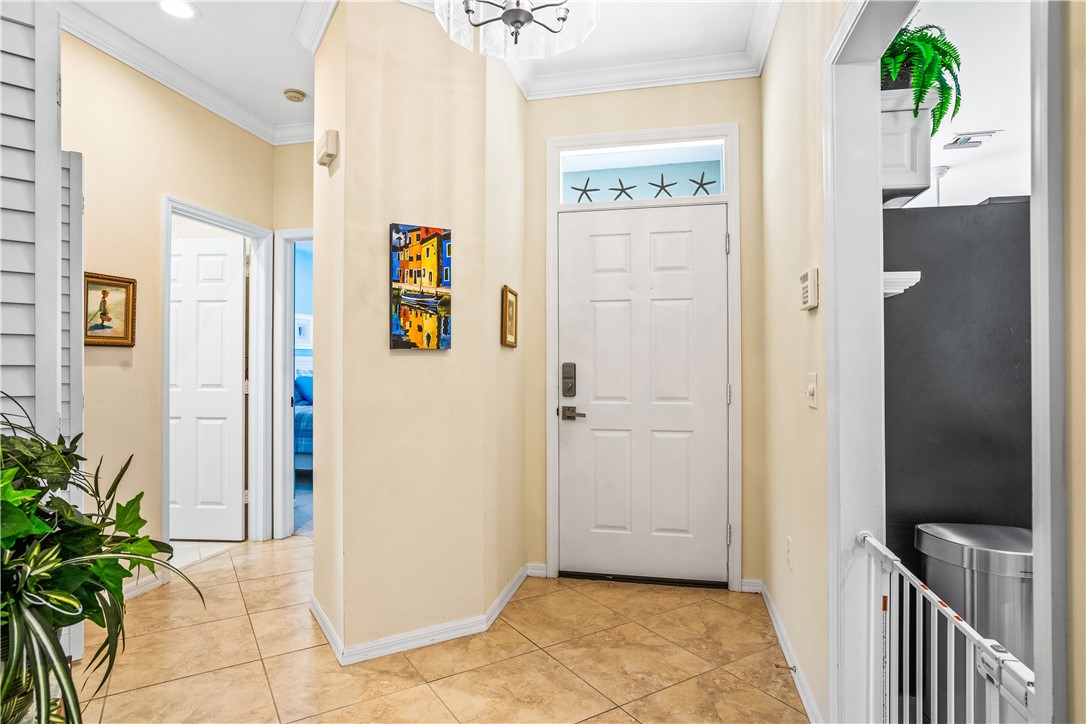 Entrance foyer with crown molding, suspended lighting, and light tile patterned floors