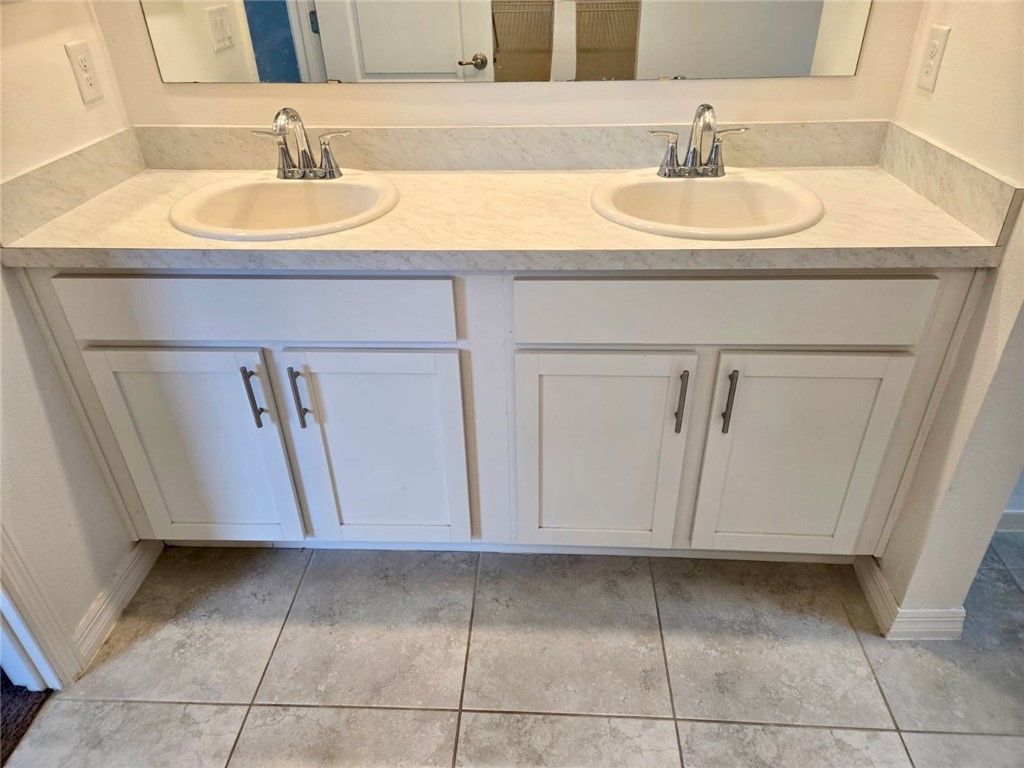 Dual vanity with white cabinetry, integrated sinks, chrome fixtures, and a light-toned countertop