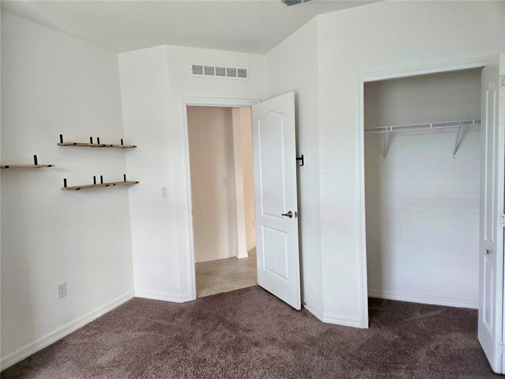 Carpeted room featuring white walls, baseboards, and crown molding