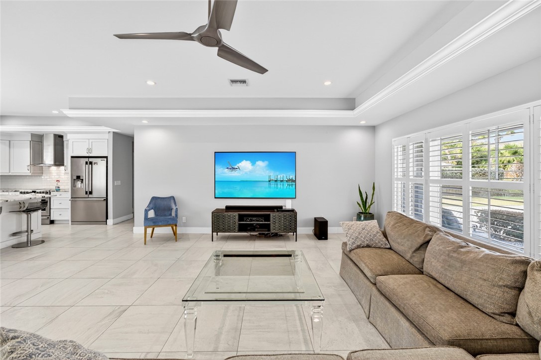 Living area featuring ceiling fan, a tray ceiling, and recessed lighting