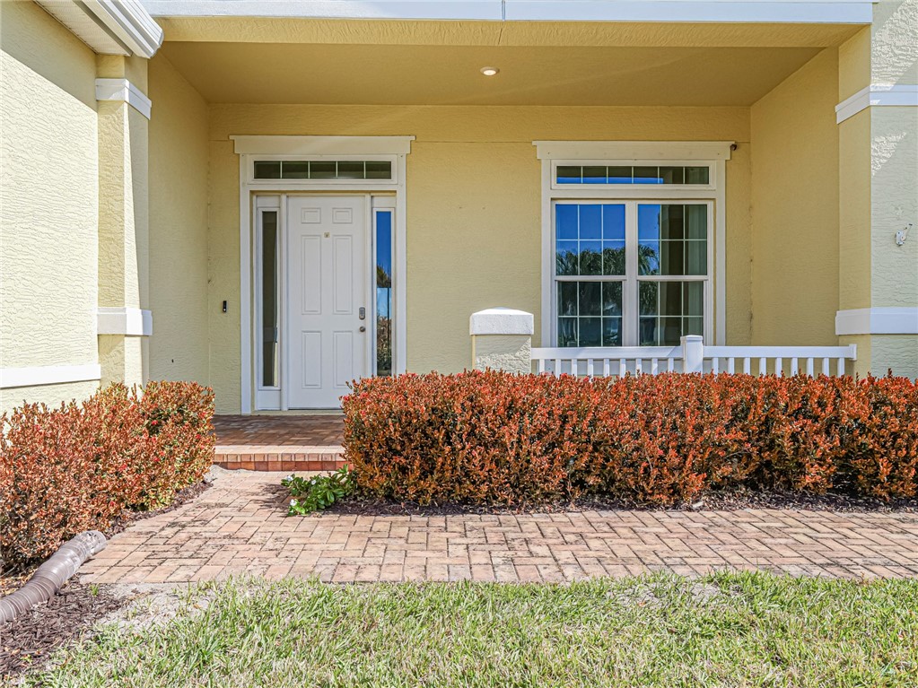 Doorway to property featuring covered porch and stucco siding
