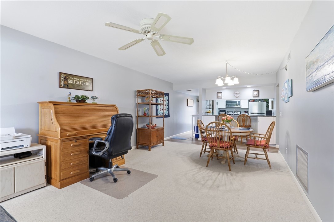 Carpeted office featuring ceiling fan and hanging lights