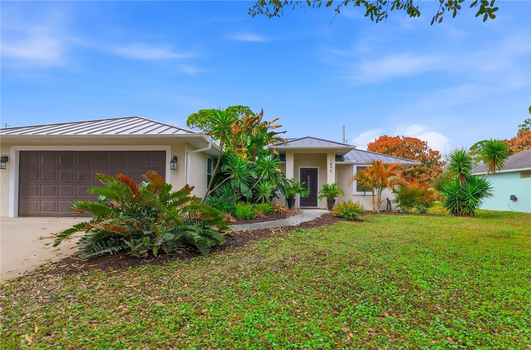 Ranch-style home featuring a standing seam roof, concrete driveway, and stucco siding