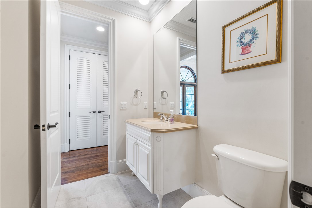 Half Bathroom with vanity, ornamental molding, and light tile patterned flooring