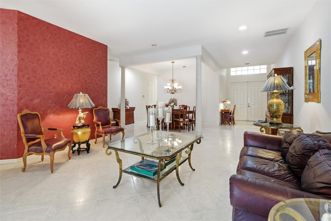 Spacious interior featuring light-toned tile flooring, a prominent red accent wall, and a double-door entry with transom windows