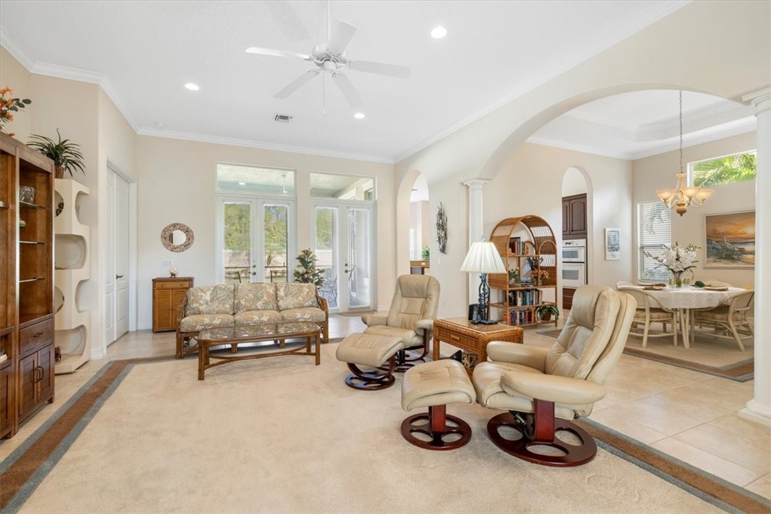 Living room featuring ornamental molding, arched walkways, recessed lighting, ceiling fan, and ornate columns