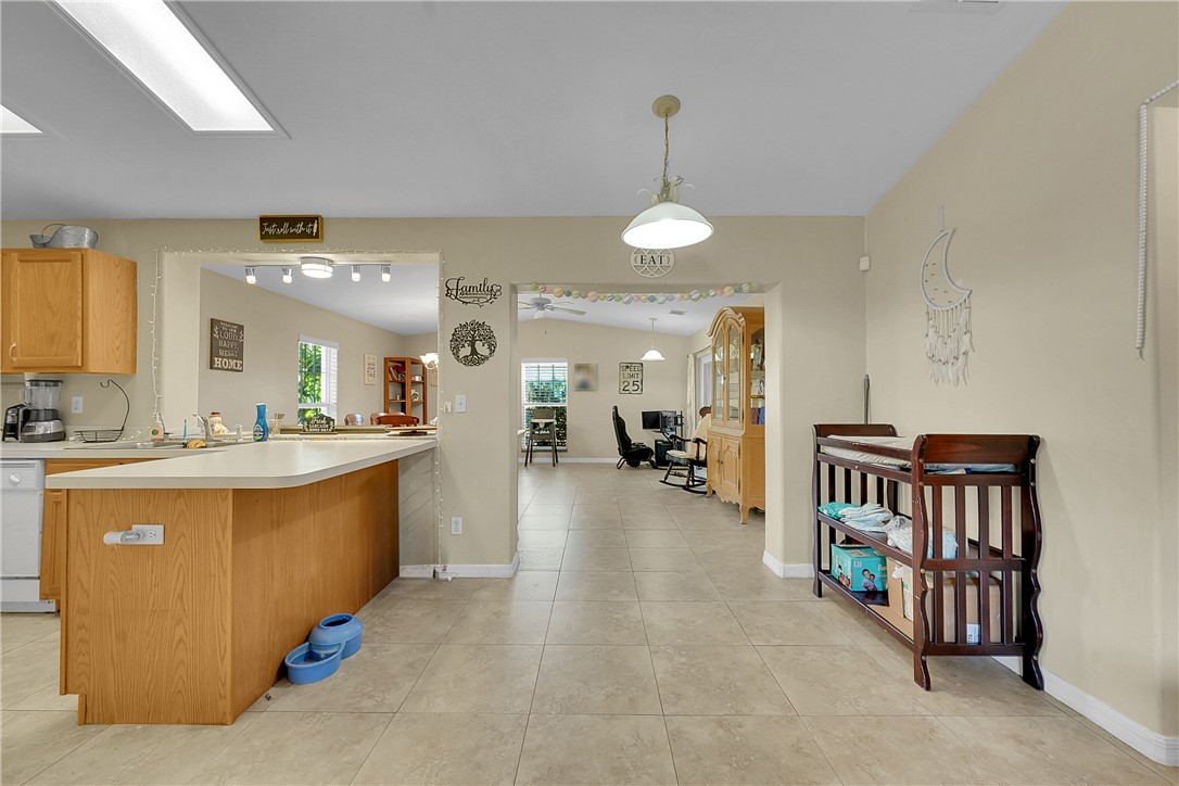 Kitchen featuring light countertops, hanging light fixtures, a peninsula, white dishwasher, and light tile patterned floors