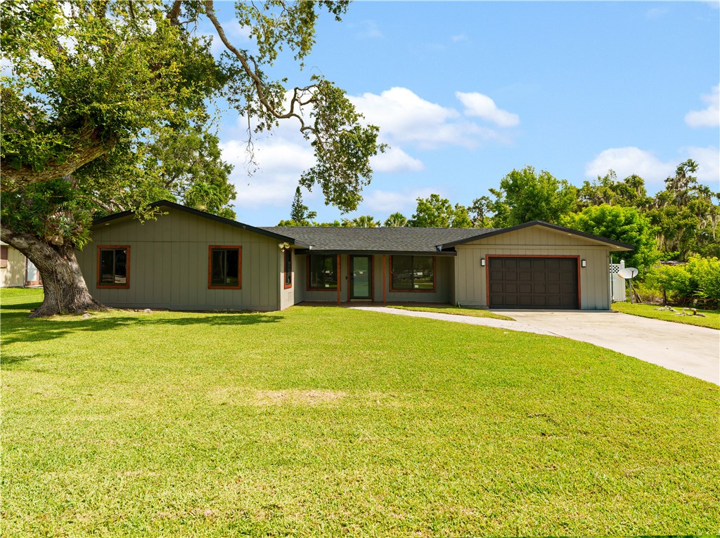 Ranch-style home featuring concrete driveway, a front lawn, and an attached garage