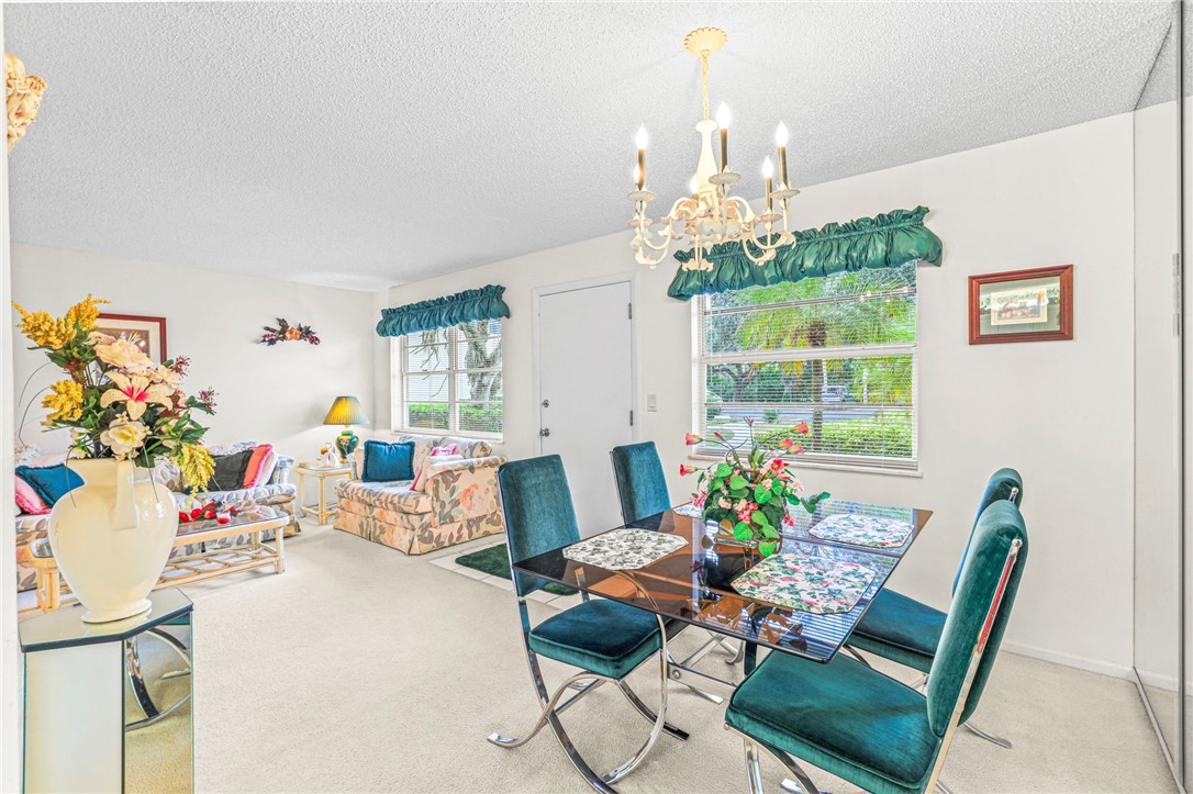 Carpeted dining space with a textured ceiling and a chandelier