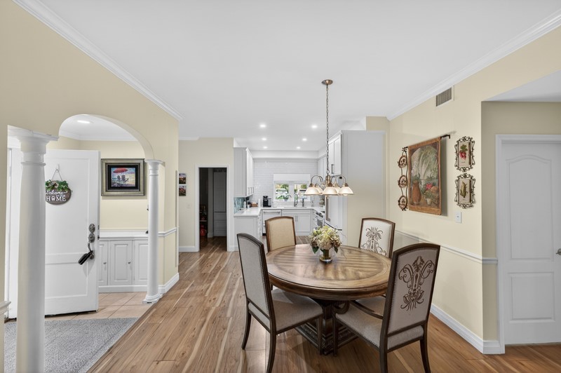 Dining area featuring light wood-type flooring, crown molding, arched walkways, recessed lighting, and decorative columns