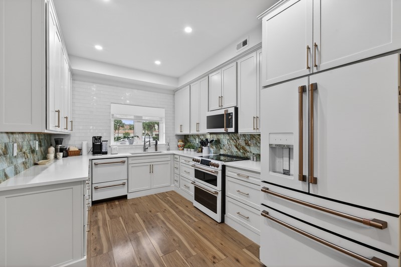 Kitchen featuring white appliances, white cabinets, light wood-style floors, recessed lighting, and light stone countertops