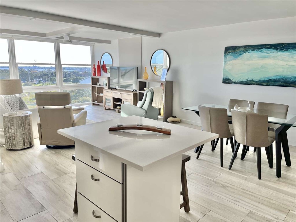 Kitchen with beam ceiling, wood tiled floors, a center island, white cabinetry, and a breakfast bar