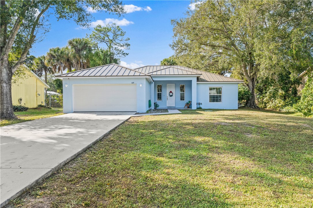 Ranch-style home featuring a metal roof, a standing seam roof, concrete driveway, and stucco siding