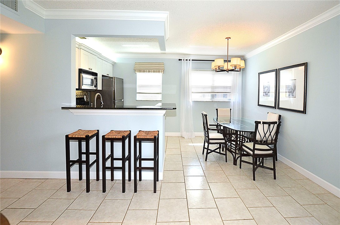 Dining area featuring crown molding, light tile patterned floors, a chandelier, and a textured ceiling