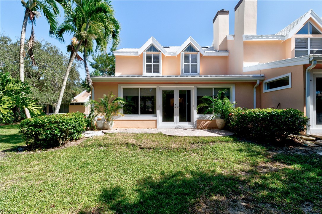 Back of property featuring stucco siding, a chimney, and a lawn