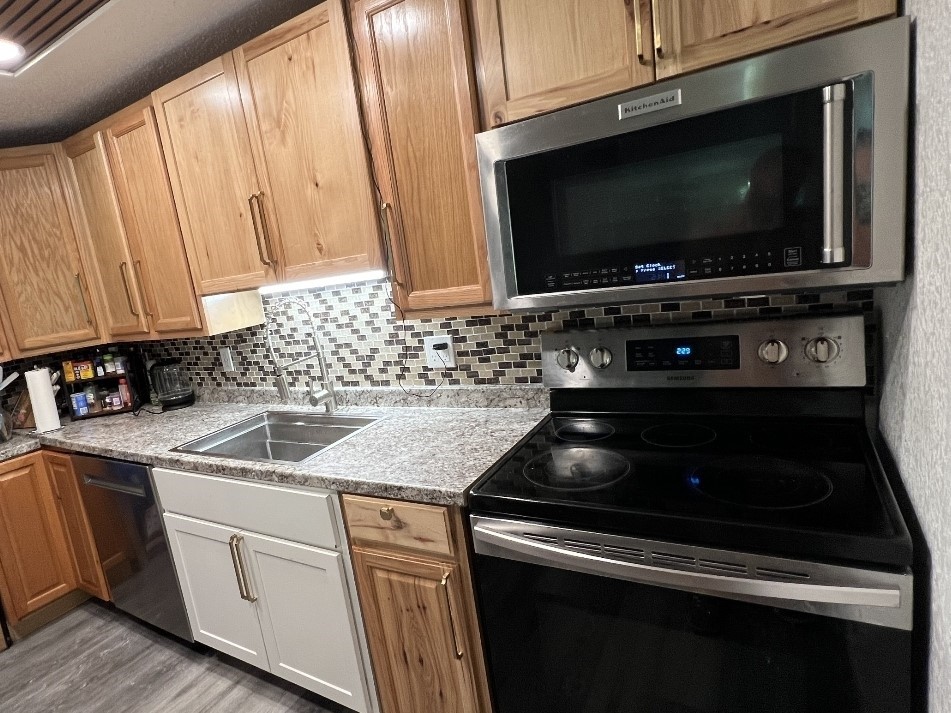 Kitchen with stainless steel appliances, backsplash, light countertops, and light wood-type flooring