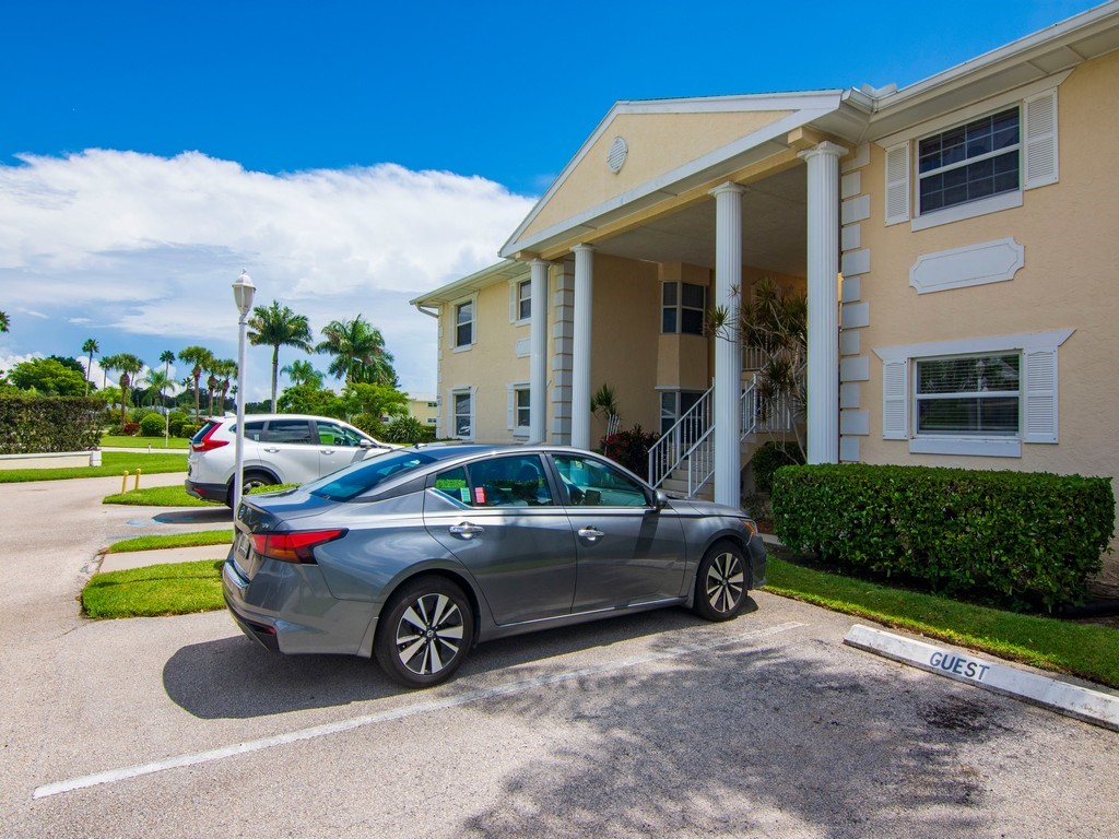 View of front of property featuring covered parking, guest spots and stucco siding