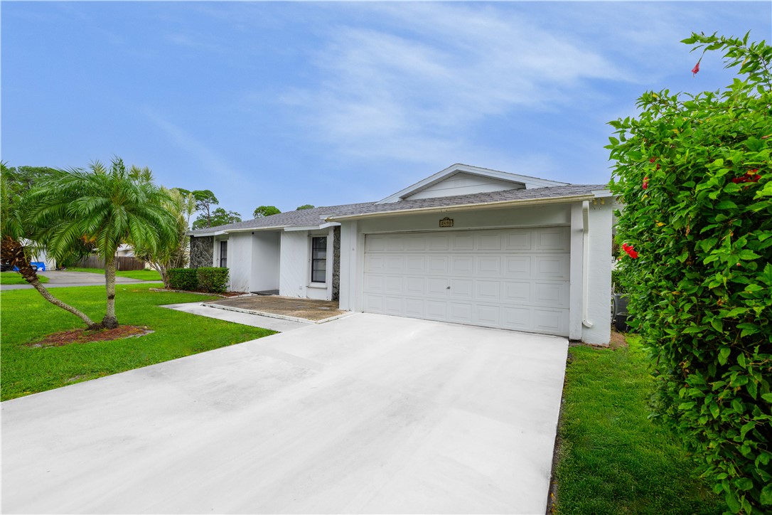 Single story home featuring a front lawn, driveway, stucco siding, and an attached garage