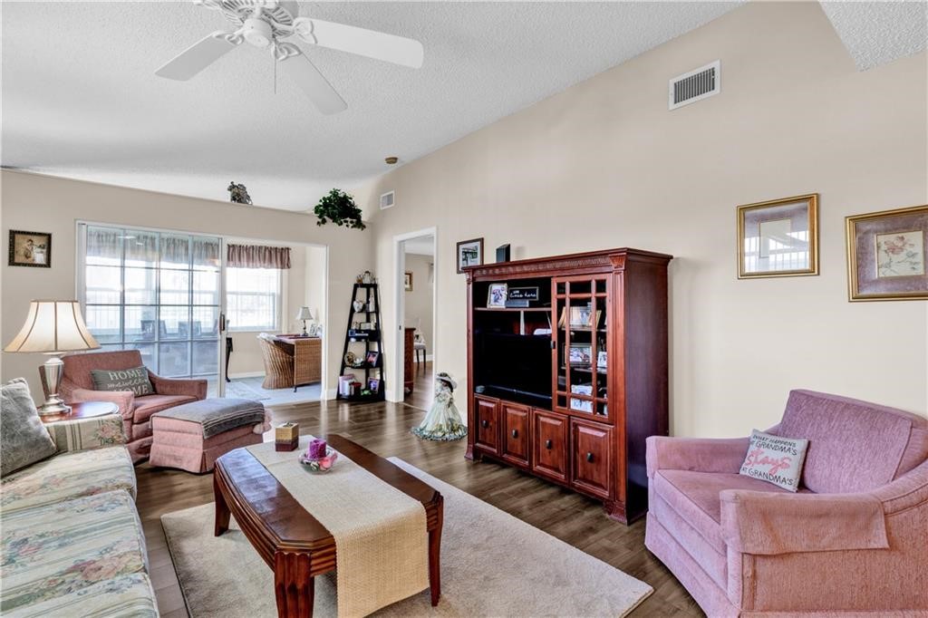 Living room featuring a textured ceiling, dark wood-style floors, and ceiling fan
