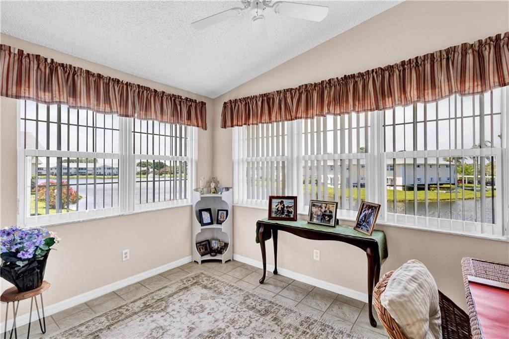 Office area with a textured ceiling, vaulted ceiling, tile patterned floors, and ceiling fan